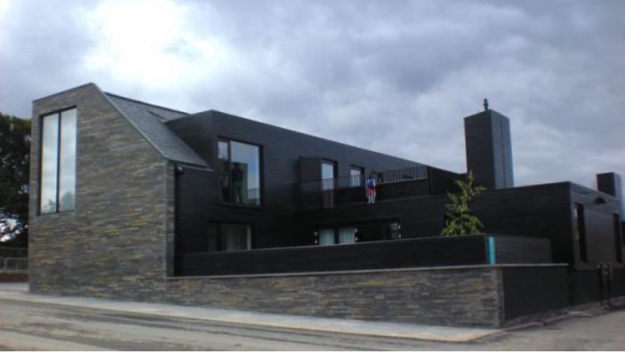 a photograph of a two storey house made from a dark material