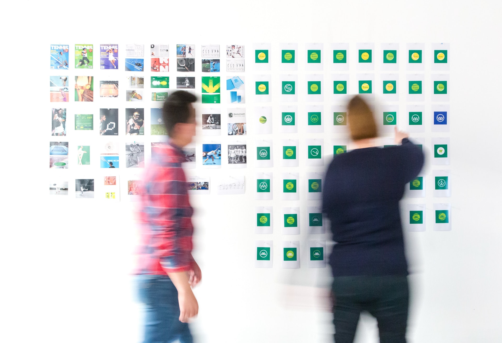 two people stand at a white wall covered with colourful graphics creating a storyboard