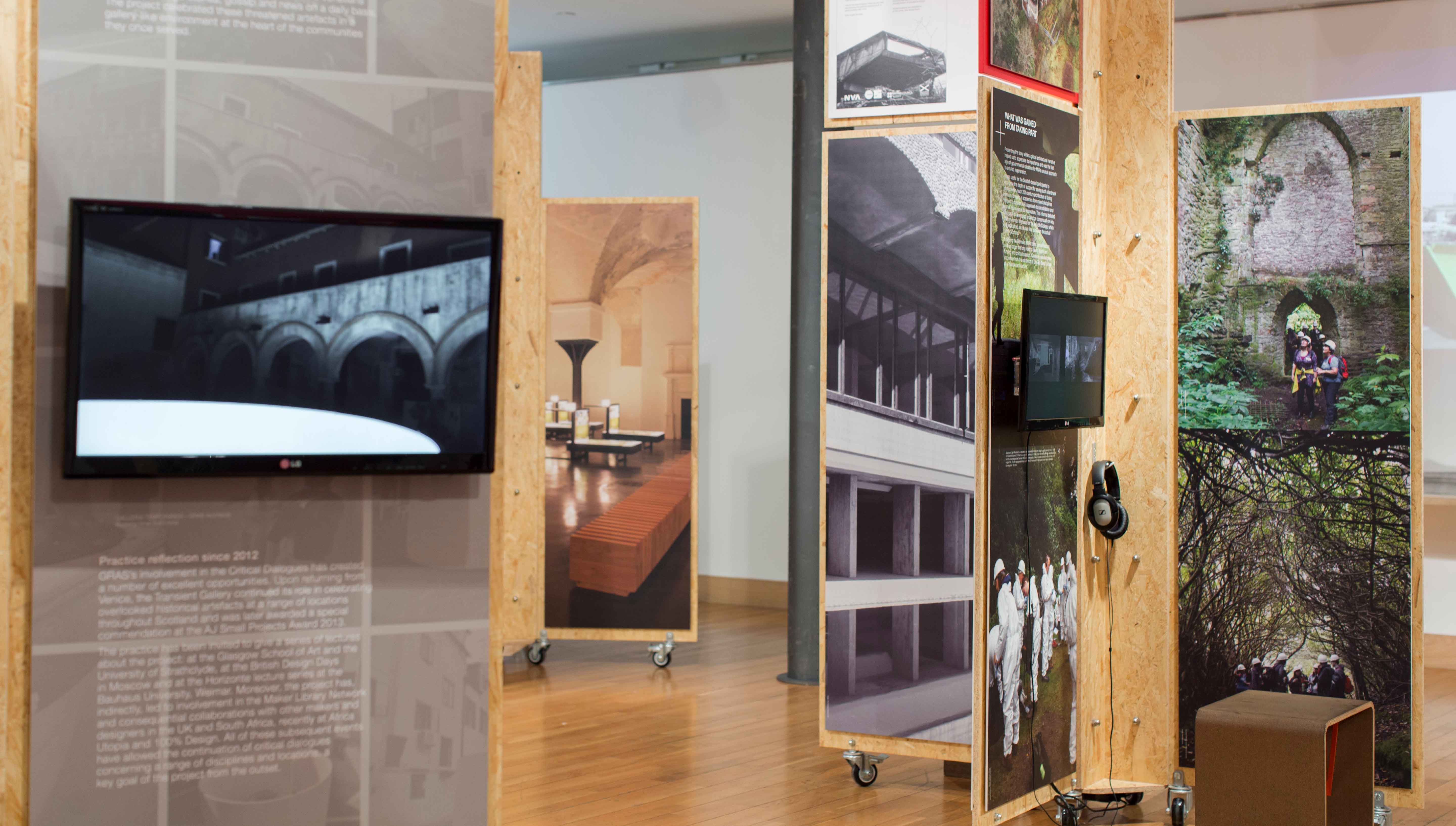 Indoor space of Past and Future exhibition with floor to ceiling room separators featuring images and tv screens.