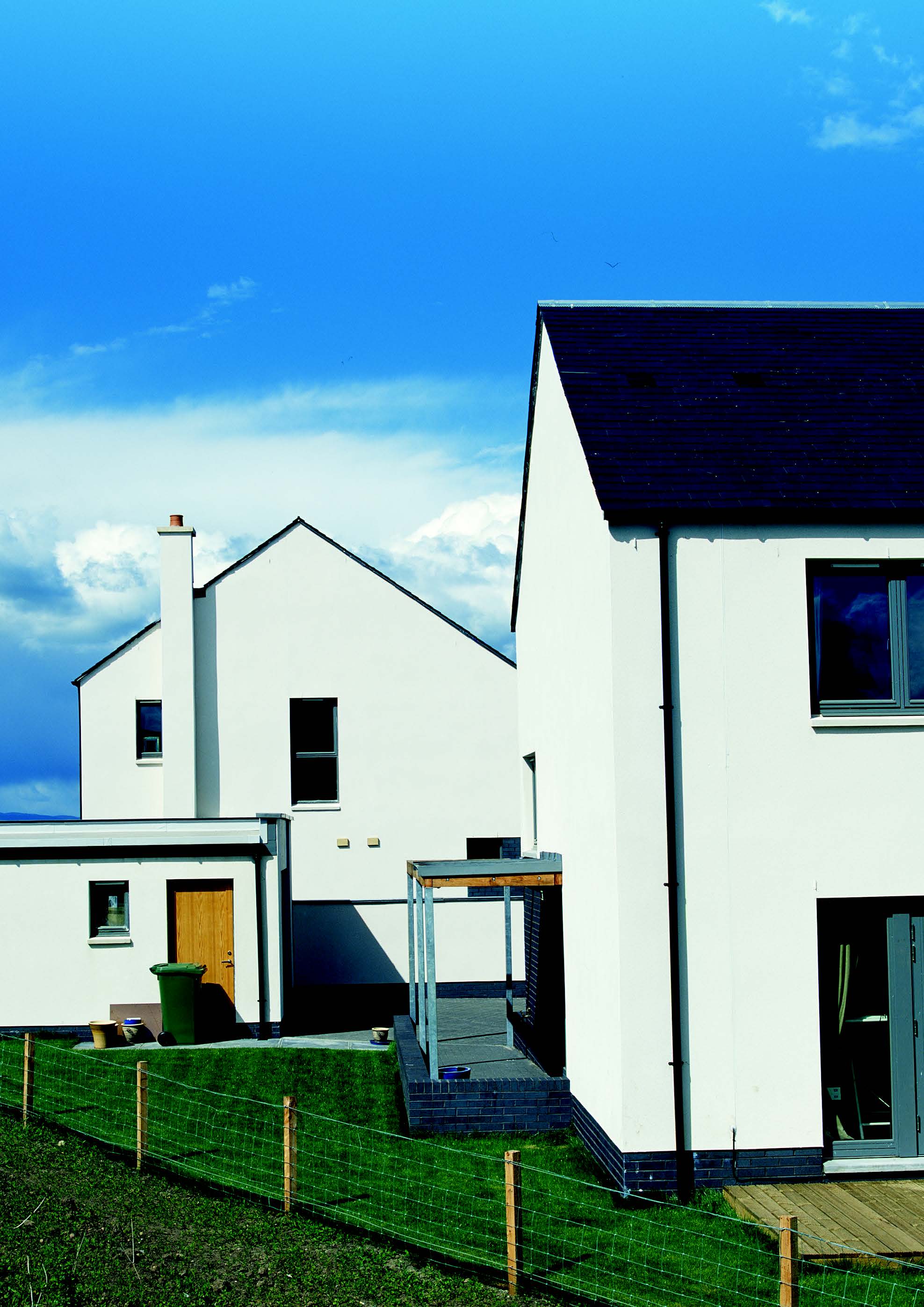 Two examples of the houses at the Maryfield Housing development and a small back garden with green grass.