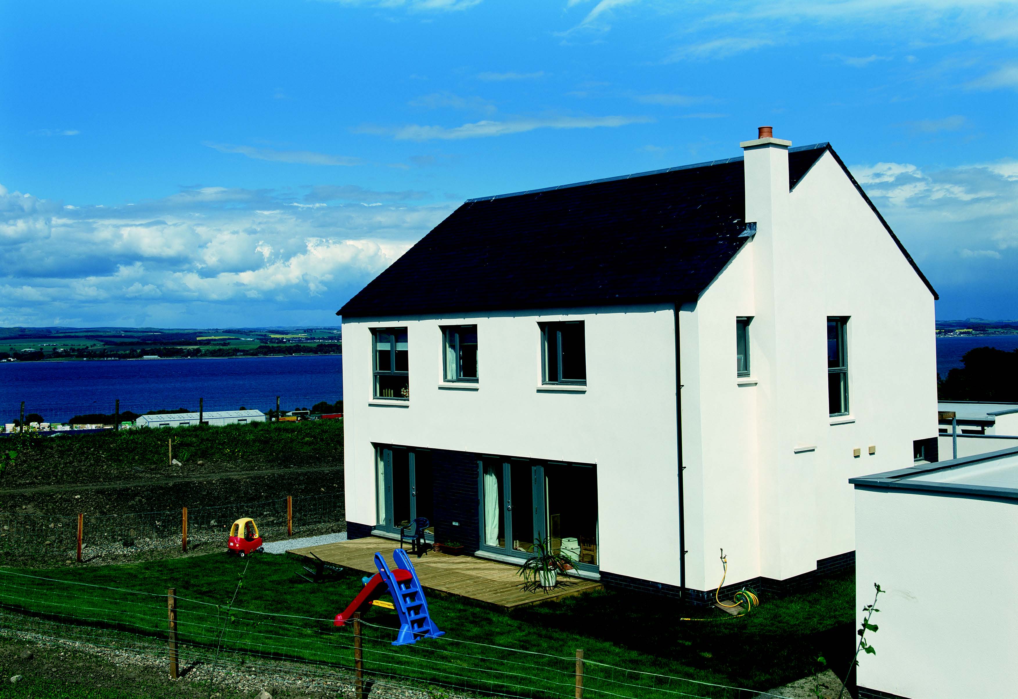 A two-storey house from Maryfield Housing development. The house has a grey coloured slated roof and white external painted walls.