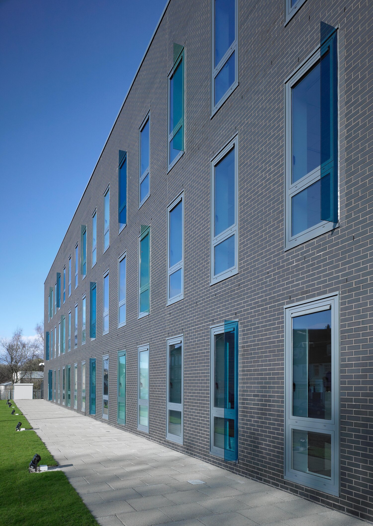 Dark grey brick facade across the street elevation of Renfrew Health and Social Care Centre. Windows line across all levels of the building.