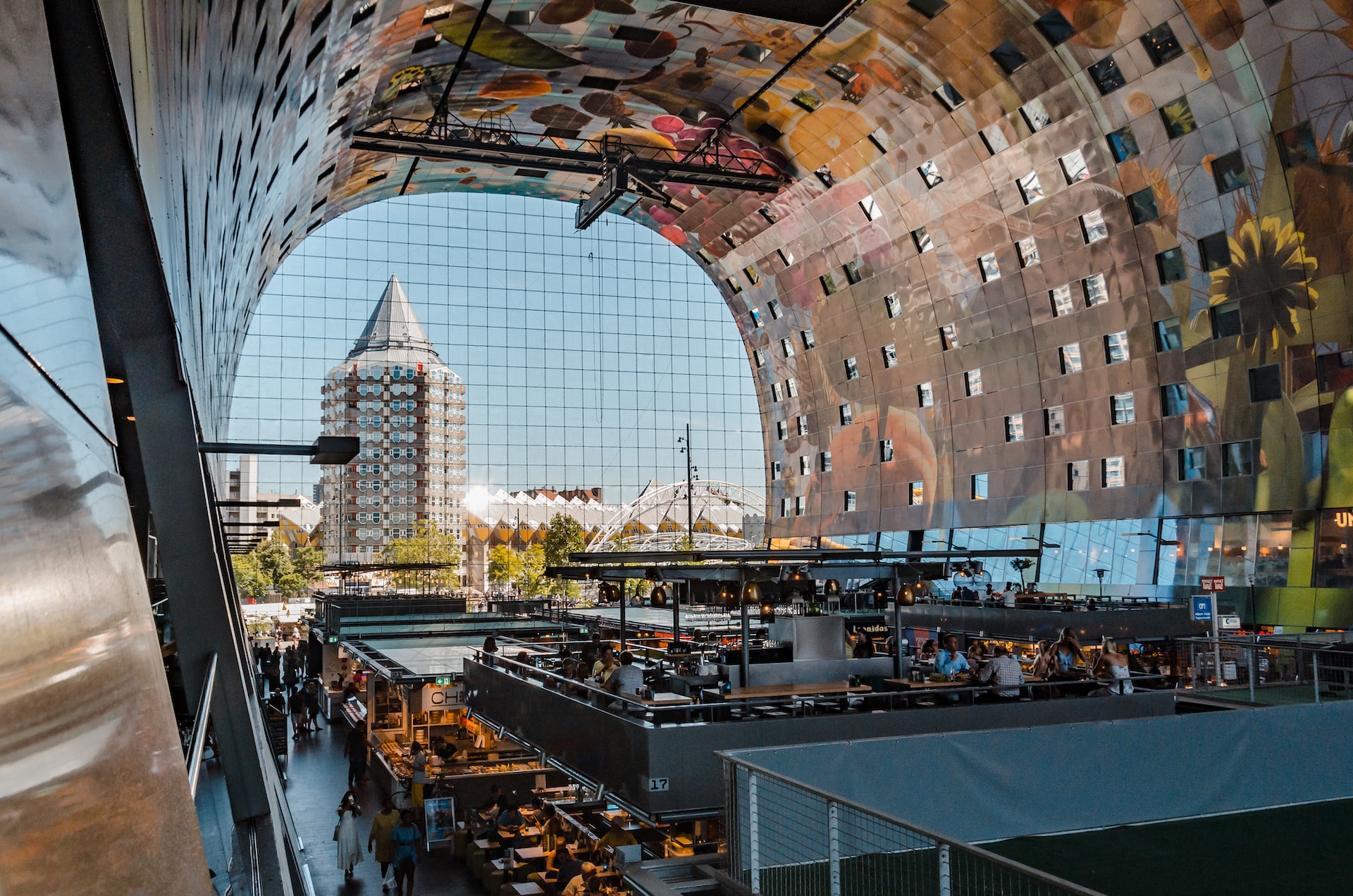 A photograph of the interior of an innovative market hall in Rotterdam which includes apartments looking into a covered market hall with large scale graphics of plants and flowers 
