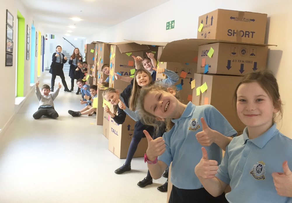 Pupils smiling in a corridor with their thumbs up at Our Lady of The Missions School in Edinburgh.