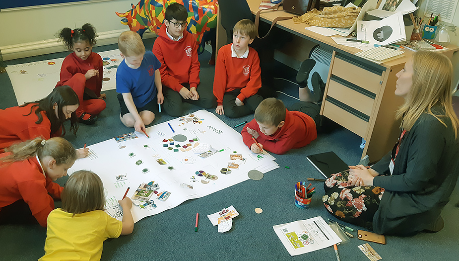 Pupils sit on the floor in the classroom at Corstorphine Primary work together to design ideas for their learning space.