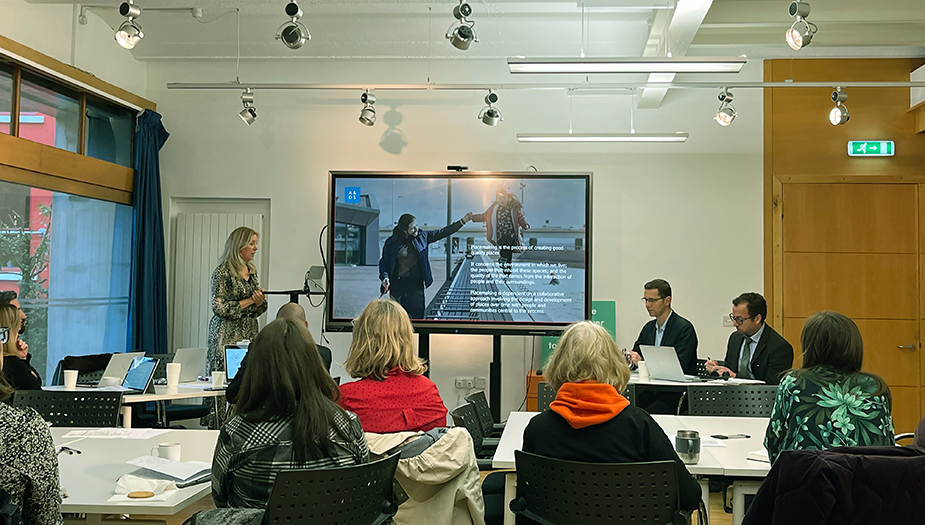 Gillian Black presenting at the LAUDF16 event. There is a big screen with an image of a father and daughter and people sat around tables in the room.