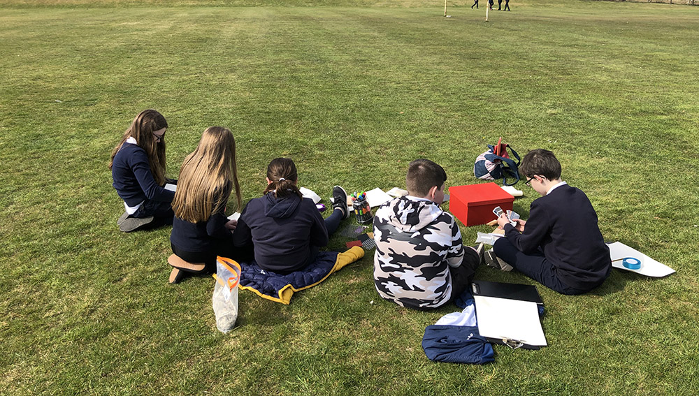 Pupils sat on the grass at their school field during a Test of Change workshop.