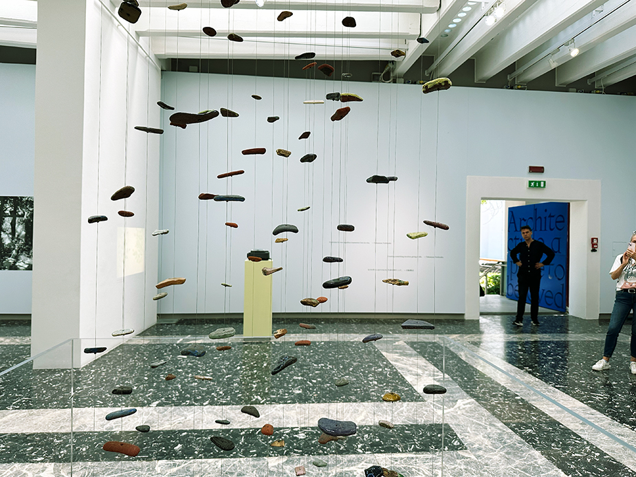 Abstract shapes of materials hang on pieces of string in an exhibition space at the 18th La Biennale di Venezia.