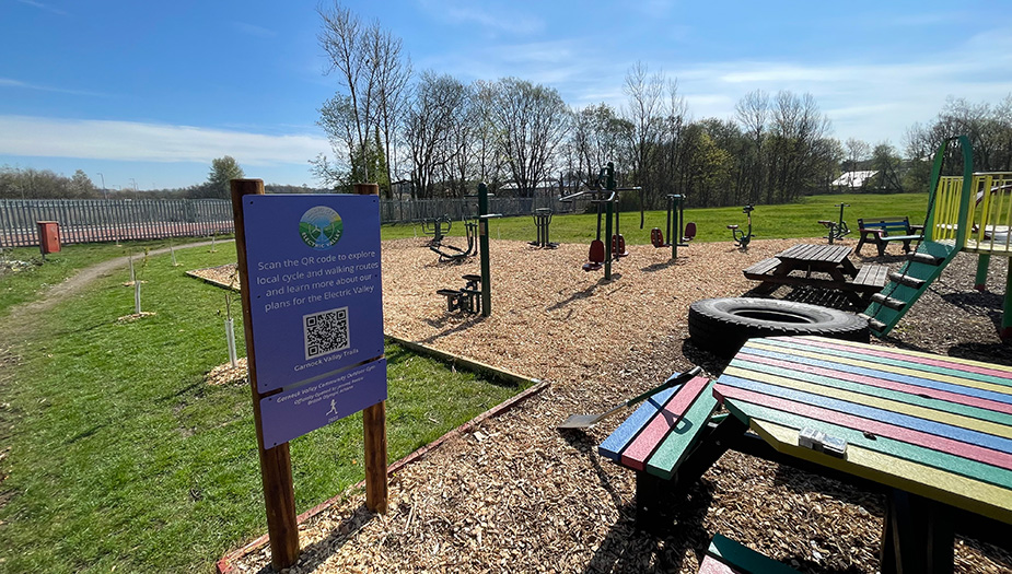 An outdoor gym on a sunny day surrounded by green spaces such as trees and trees.