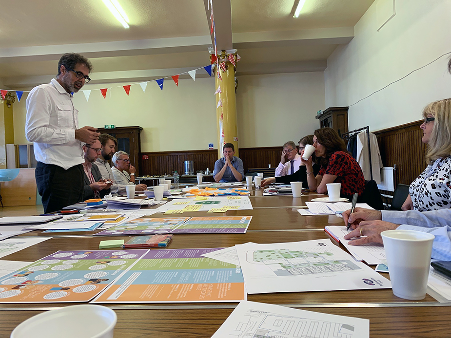 A&DS staff present the Arnott's Backland development in a methodist halls workshop in Paisley. The Housing to 2040 workshop handouts surround the table with bunting decked overhead.