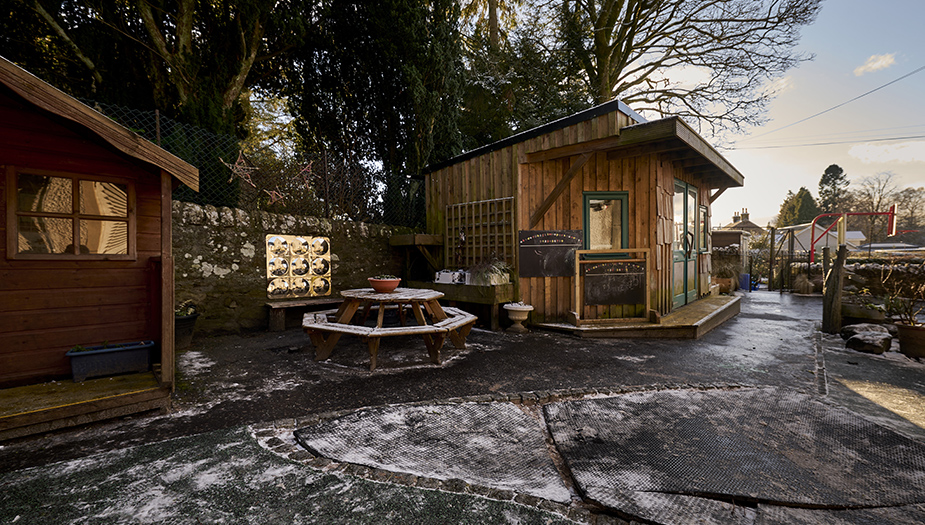 An outdoor learning area at St Mary's Dunblane Primary that includes a round seating area, a shed and spaces to play.