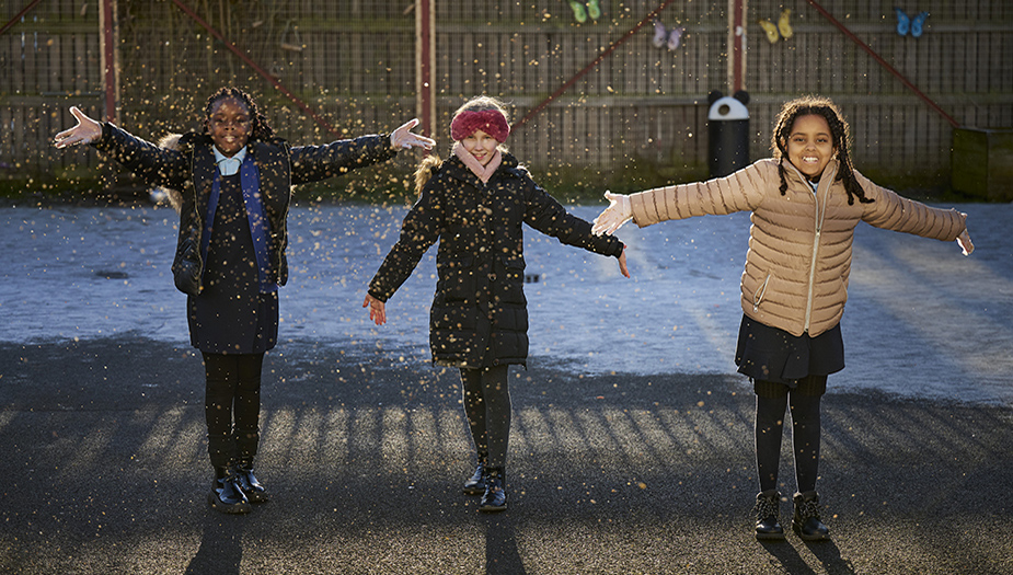 Three pupils at St Michaels Primary lift snow into the air.