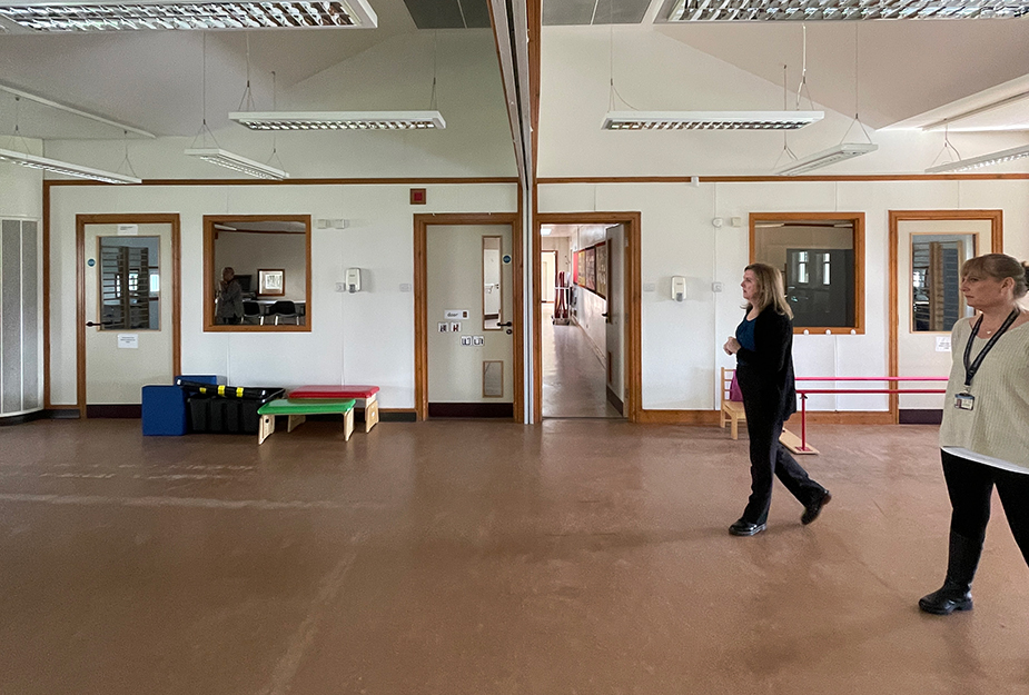 Two people walking towards a partition wall in a large nursery space.