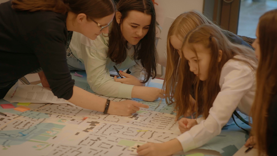 Young people gathering around a table looking at a map