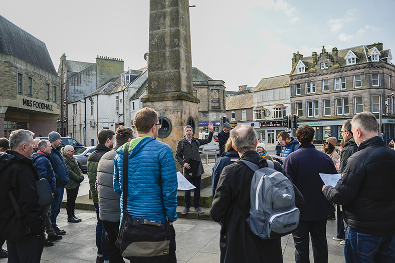 People standing around a monument during a walking tour in Inverness.
