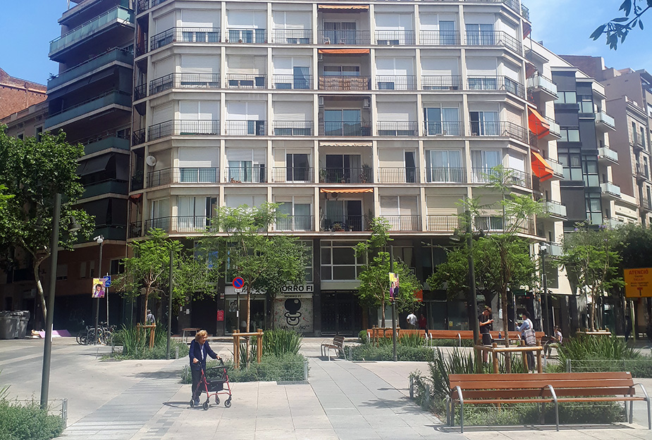 An elderly woman walks through a square in front of a Superblock in Barcelona.