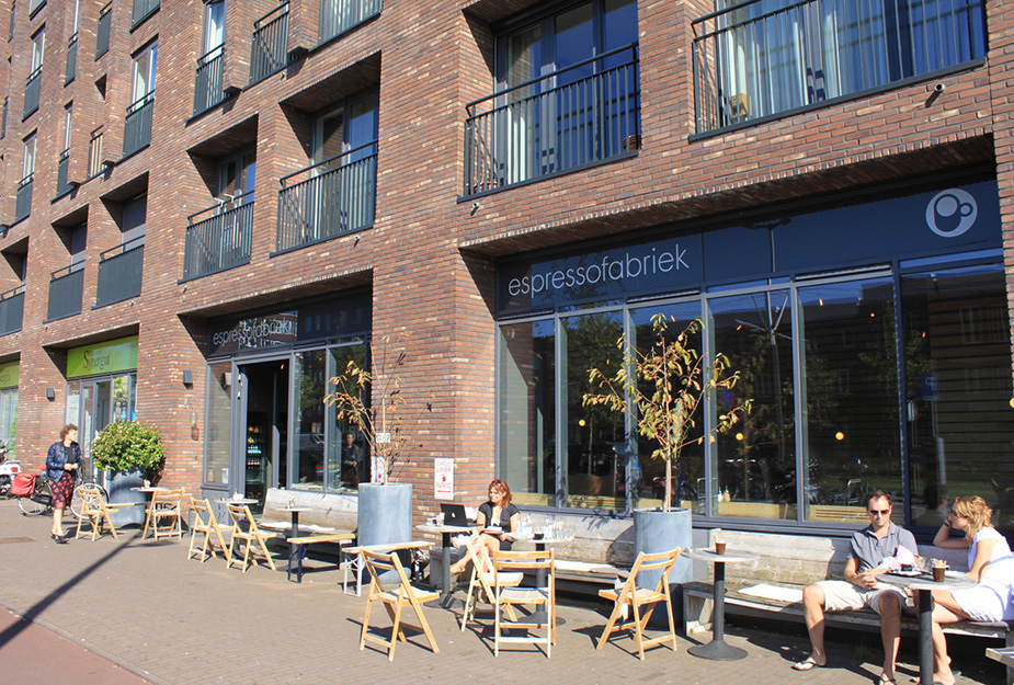 People sitting outside a coffee shop below apartments in Holland.