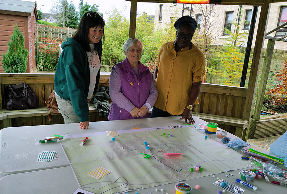 Attendees at the Place Standard Armadale event pose above a map and smilling at The Den venue.
