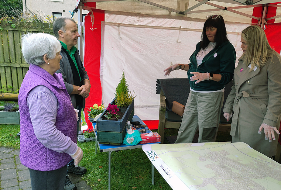 People standing in a tent and talking around a wooden planter at the Place Standard Armadale event.