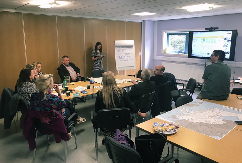 A group of people at a Key Agencies Group workshop in Caithness sat around a table and talking.