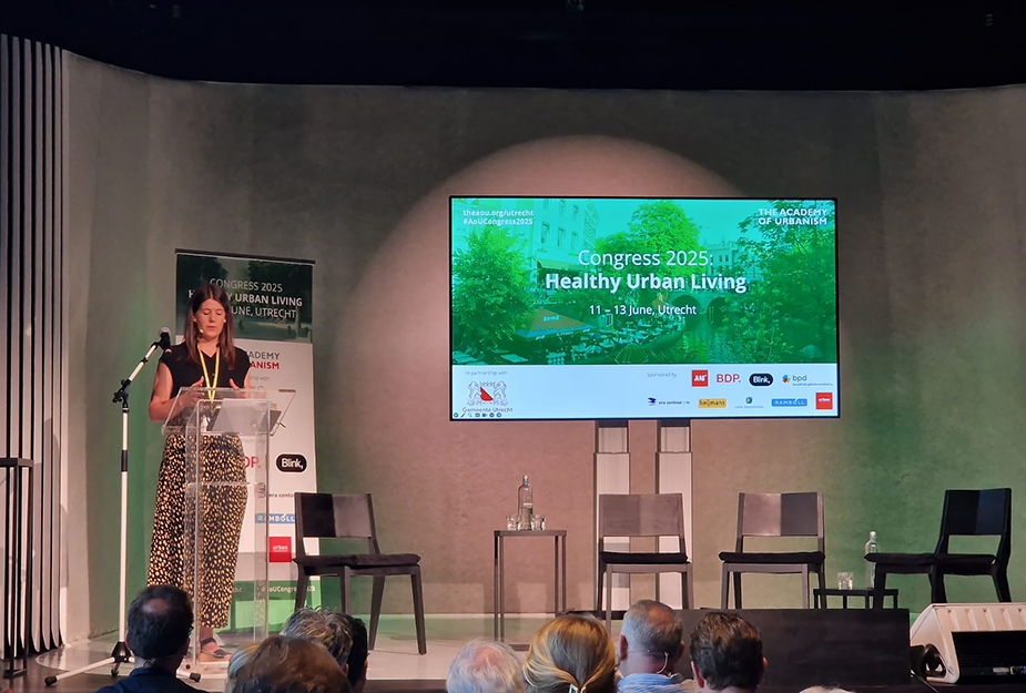 Heather Claridge standing at a podium beside a presentation screen.