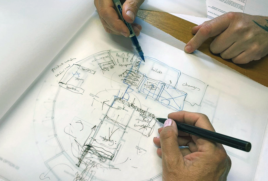 Architectural drawing of a nuresery space by two people who have their hands holding pens.