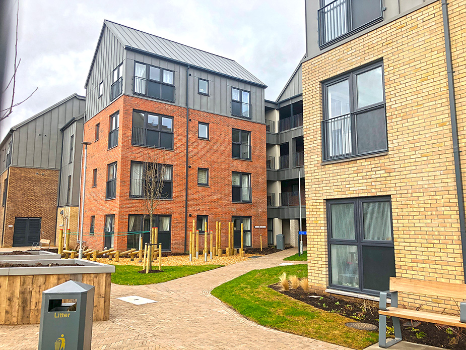 Four story housing development with gardens, raised beds and a seating area.