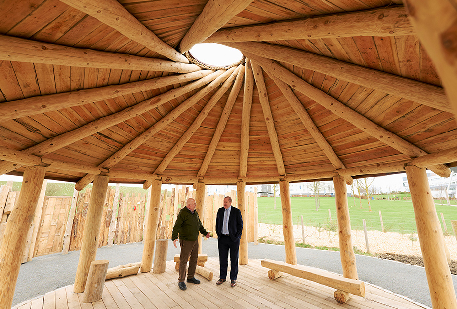Patrick Boxhall and Graeme Dey having a conversation inside The Howff which includes a circular roof and beams surrounded by green grass.