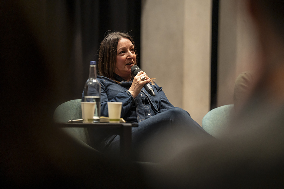 Caroline Parkinson speaking into a micrphone whilst sat down on a chair at the AI in the City event.