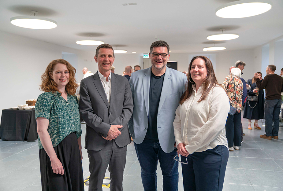 Four people smiling at the camera at an event.