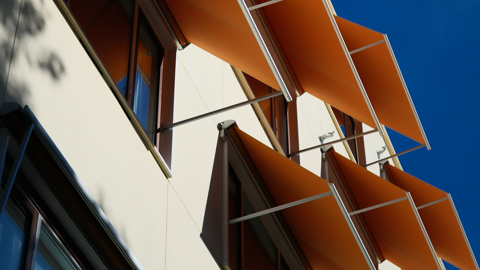 A modern building with orange awnings on windows.