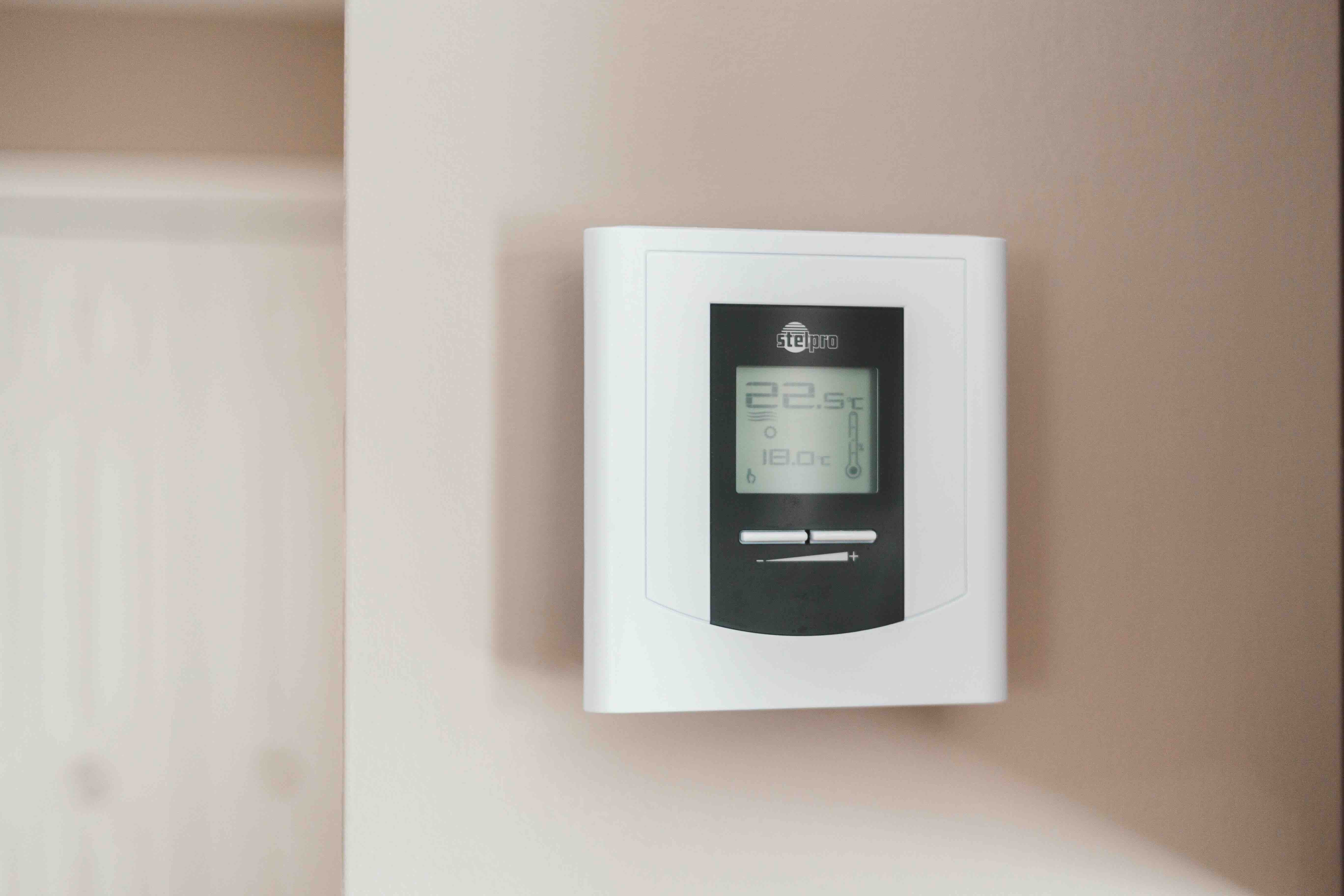A close up image of a domestic thermostat on a beige wall